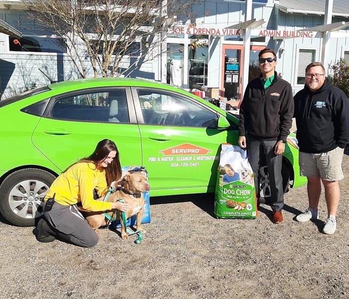 SERVPRO car with reps in front with Humane Society reps and dog